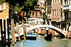 Gondolier Passing Under A Bridge On A Rio In Venice