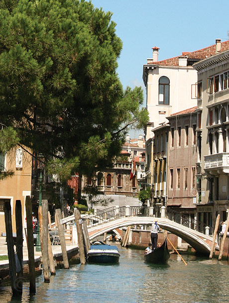 Gondoliere passando sotto un ponte su un rio a venezia foto
